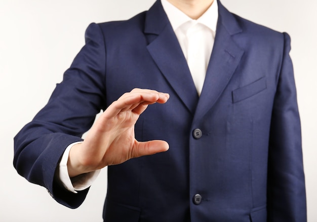 Businessman showing anything on grey wall