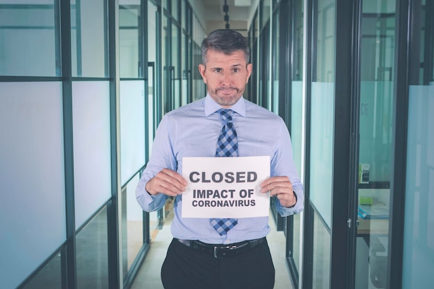 Businessman showing closed impact of coronavirus text