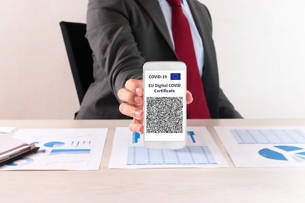 彼のヨーロッパのcovidワクチン証明書を示すビジネスマン
