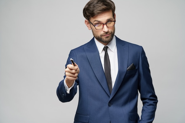 businessman showing pen or pencil at camera over gray background