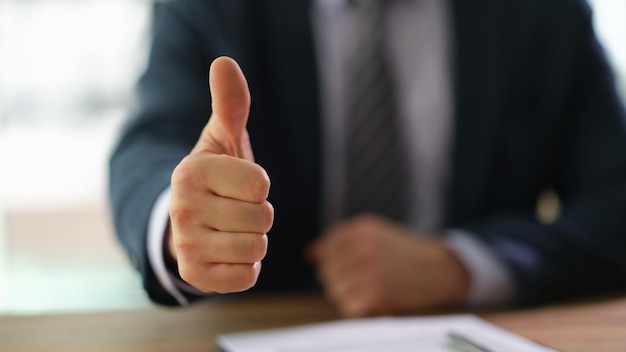 Photo businessman showing thumb up at work in office closeup