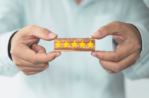 Businessman showing yellow five stars which print screen on wooden block cube foe customer evaluation