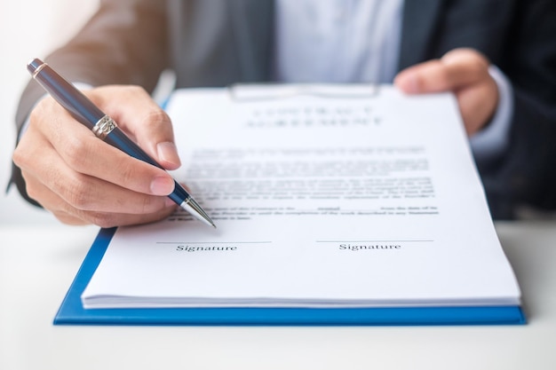 Бизнесмен подписывает контрактные документы после прочтения мужчины, держащего ручку, и утверждает бизнес-отчет Контрактное соглашение, партнерство и концепции сделки