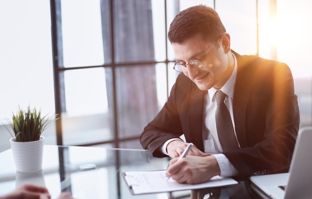 businessman signs a contract at the table in the office closeup