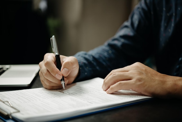 Бизнесмен подписывает документы ручкой, подписывая контракт и партнерство на столе