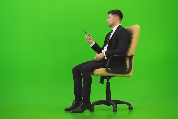 ビジネスマンは椅子に座って、緑の背景にジェスチャー