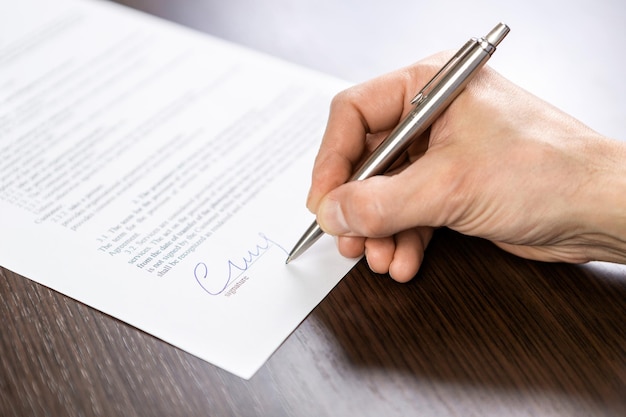 A businessman sits at an office Desk and signs a contract with a ballpoint pen