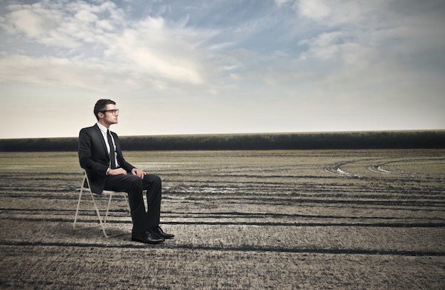 Businessman sitting on a chair in a middle of nowhere