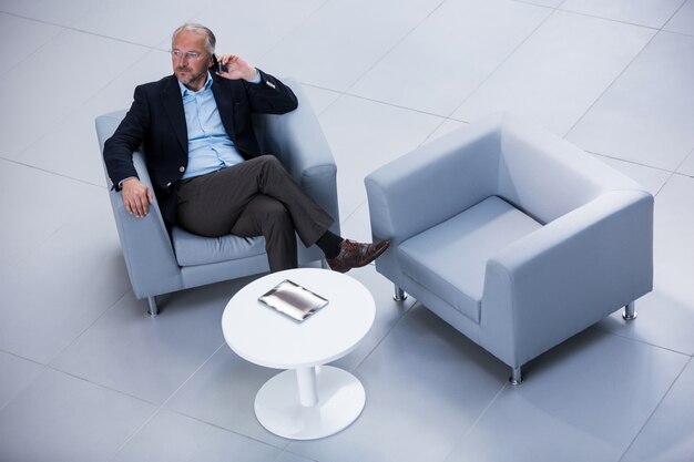 Businessman sitting on a chair and talking on mobile phone