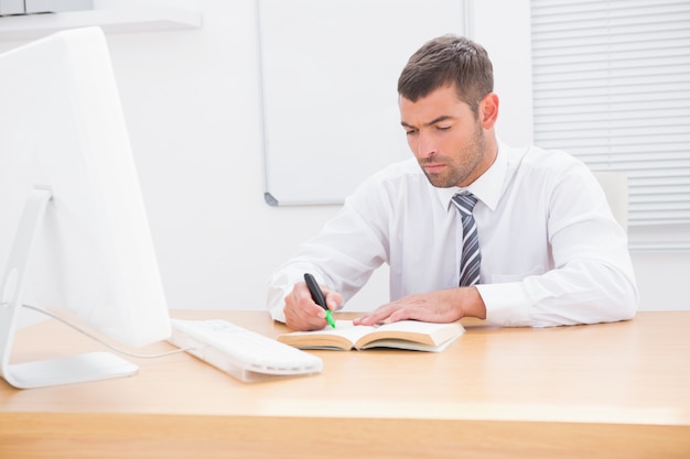 Businessman sitting at desk reading a book