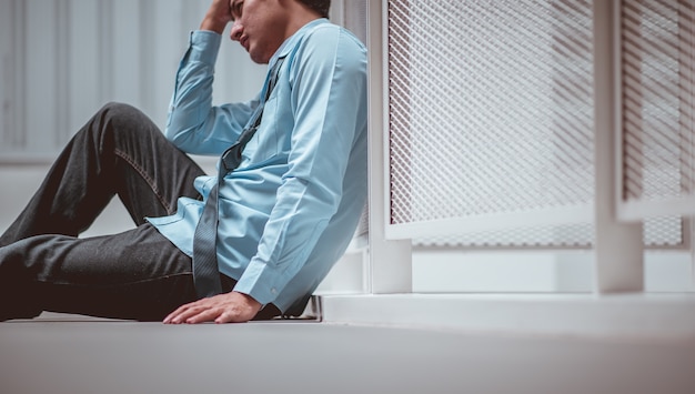 Businessman sitting on the floor after failure and layoff Man unemployed from company