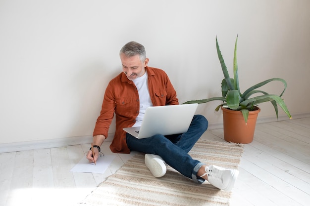 Businessman sitting on the floor in the home office and making notes