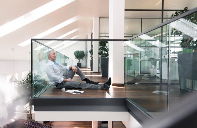 Businessman sitting on floor in the office, taking a break