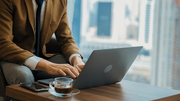 Businessman sitting on furniture working on laptop at ornamented corporate