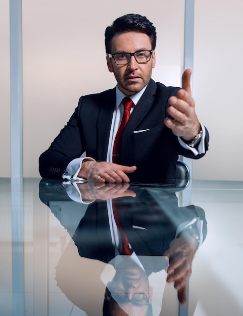 Businessman sitting at his Desk and holding out his hand for a handshakeconcept of partnership