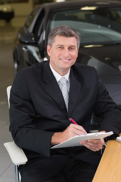 Businessman sitting at his desk while writing on clipboard