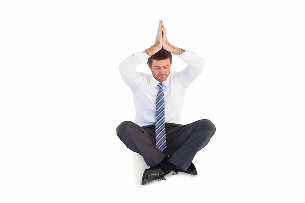 Businessman sitting in lotus pose with hands together