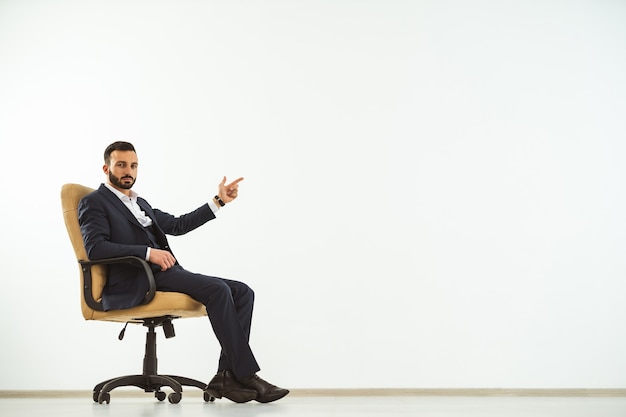 The businessman sitting on an office chair on the white background and gesturing