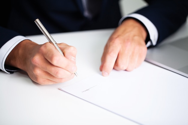 Photo businessman sitting at office desk signing contract.