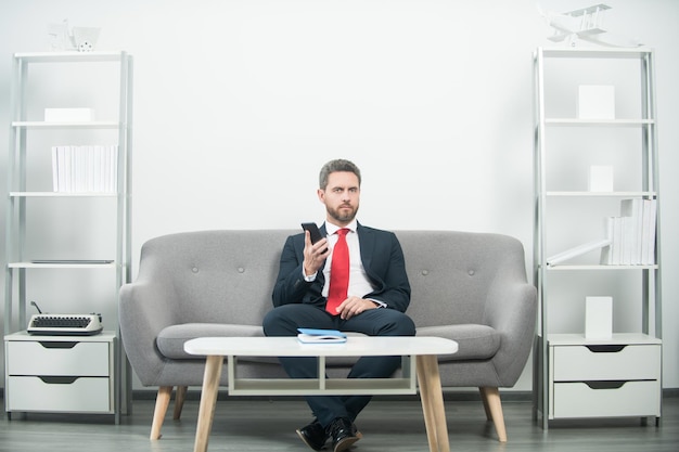 Businessman sitting in office and holding phone