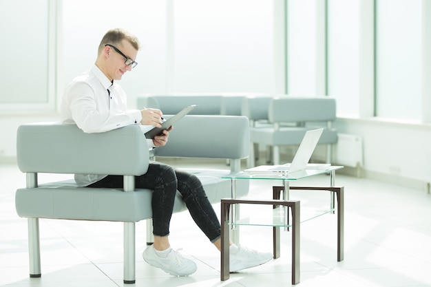 Businessman sitting in the office lobby and reading a business document. business concept