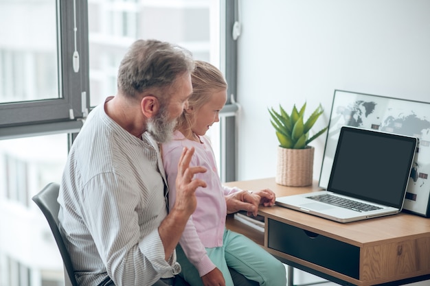 A businessman sitting at the table and holding his small daughter