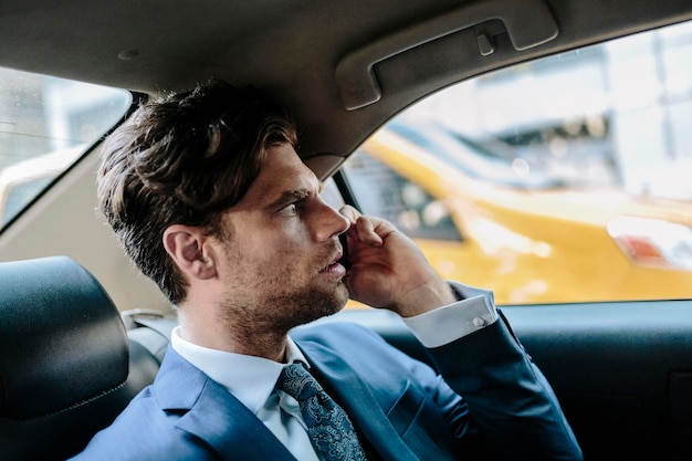 Businessman sitting in taxi, using smart phone