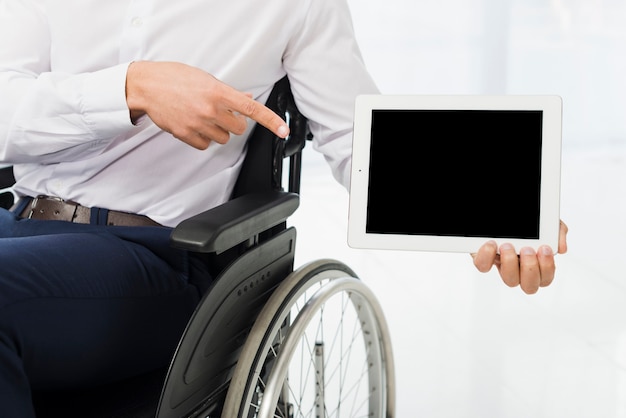 Photo businessman sitting on wheelchair pointing his finger at digital tablet