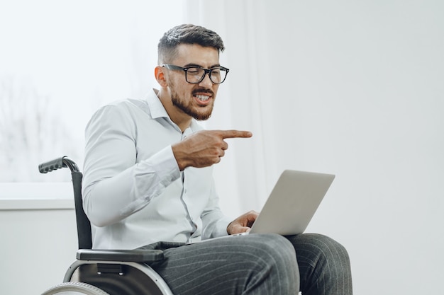 Businessman sitting in wheelchair and using laptop