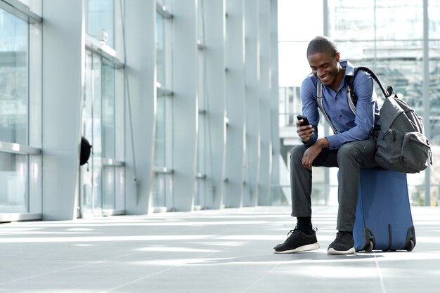 Photo businessman sitting with luggage and mobile phone at station