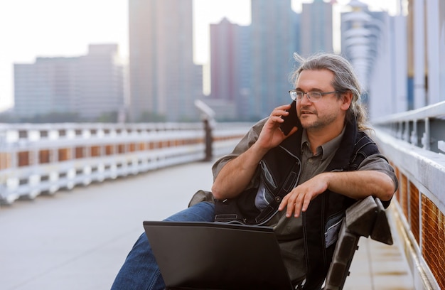 Businessman sitting on the with new york cityscape with smart phone in outdoor