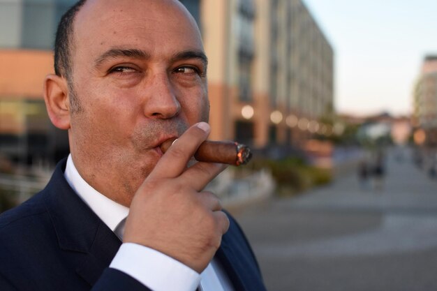 Photo businessman smoking cigar on road in city