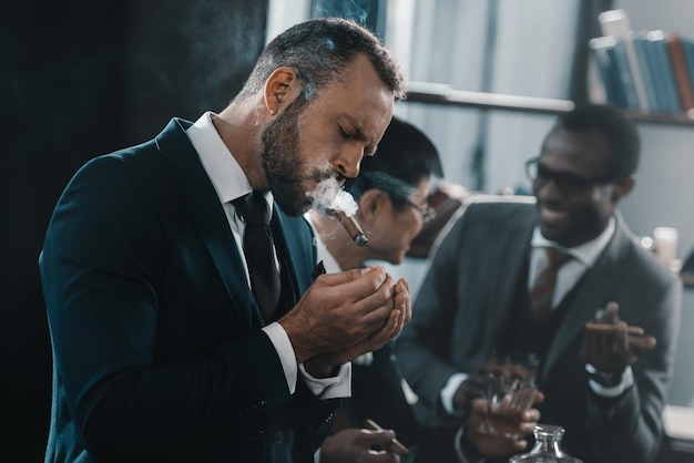 Businessman smoking cigar with multicultural business team spending time behind