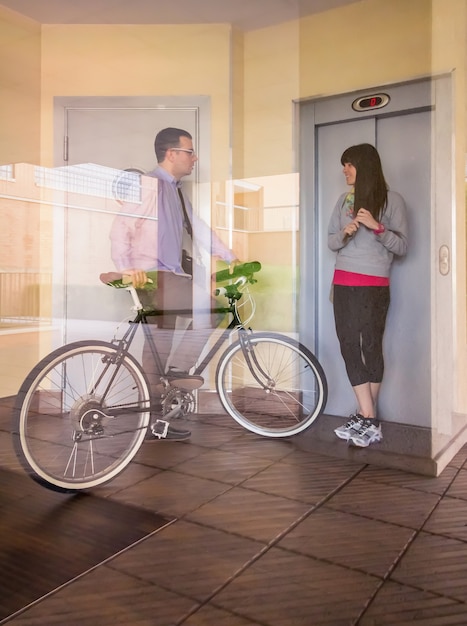 Businessman and sportive girl waving behind glass