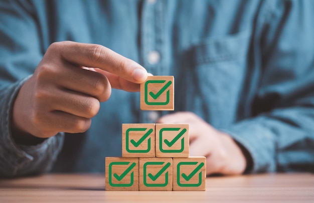 Businessman stacking green correct sign symbol which print screen on wooden block cube for document and project approve concept