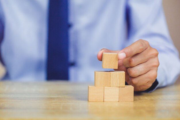 businessman stacking wooden blocks into steps. Concept of business growth success