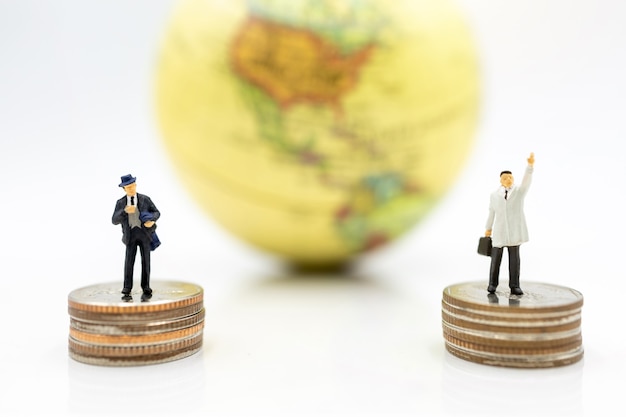 Businessman standing on coins stack with globe