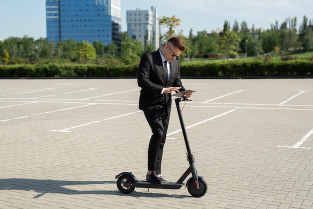 Uomo d'affari in piedi accanto a uno scooter elettrico