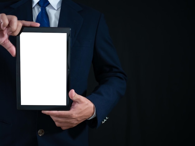 Бизнесмен стоит с планшетом с белым экраном на темном фоне Рекламная концепция Баннерный знак