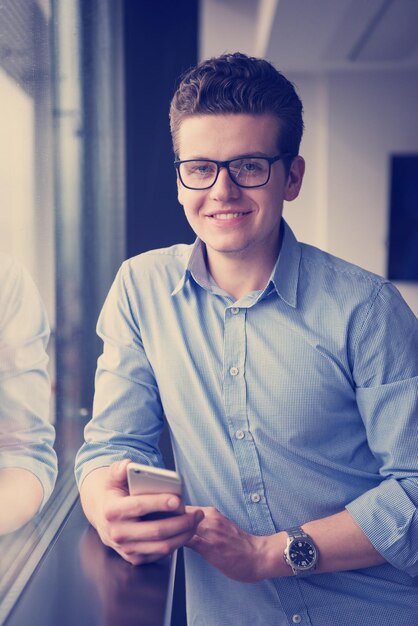 Businessman Standing In A Modern Building Near The Window With Phone