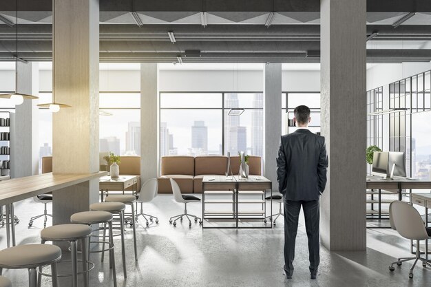 Businessman standing in modern coworking office interior with bright city view and concrete flooring Design and workplace style concept