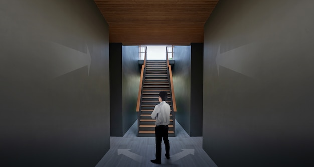 黒い壁と階段、あなたの成功を達成するための概念上の矢印の近くに立っている実業家