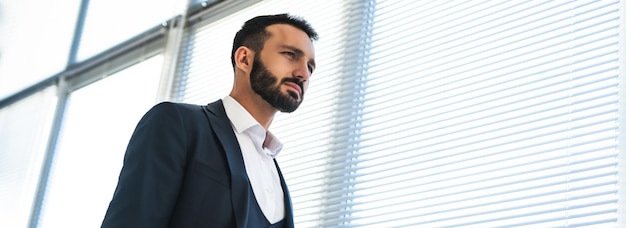 The businessman standing near blinds on the window