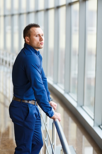 Businessman standing near the window and looking into it