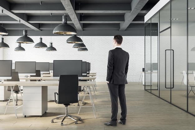 Businessman standing office interior with open space and computers