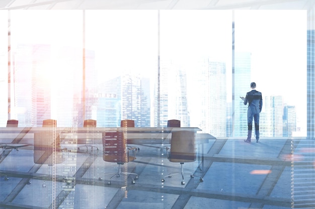 Businessman standing in an office meeting room with orange chairs and table. Panoramic windows. 3d rendering mock up toned image double exposure