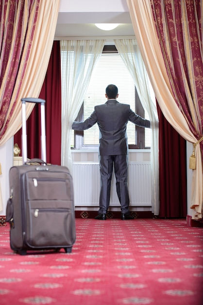 Businessman standing at window, just go to hotel room.