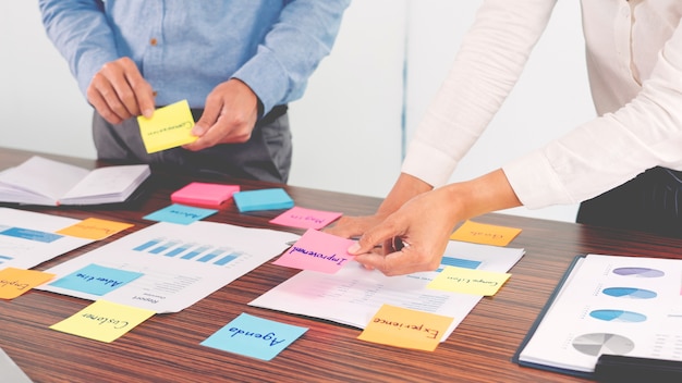 Businessman stick colorful notes to brainstorming on the table working on new project to share idea to thinking how to planning new case.