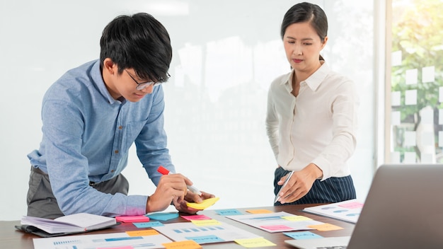 Businessman stick colorful notes to brainstorming on the table working on new project