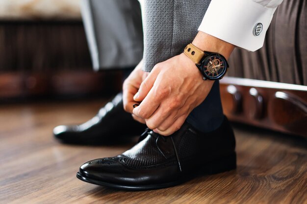 Businessman straightens shoes man prepares for work groom in the morning before the wedding ceremony